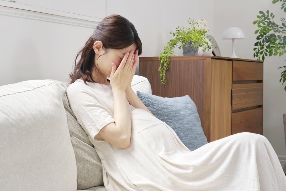 頭をかかえて悩んでいる妊娠中の女性