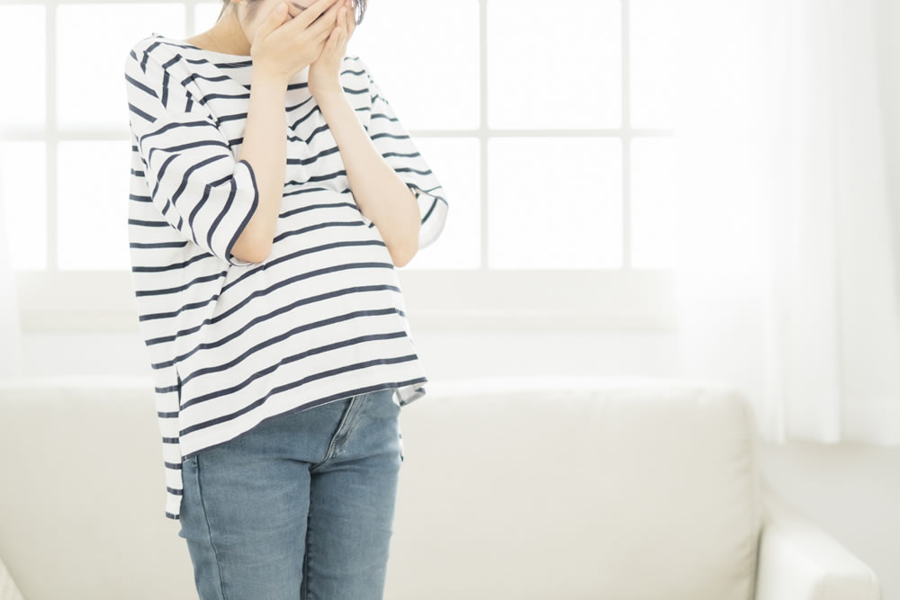 立ちながら悩んでいる妊娠中の女性