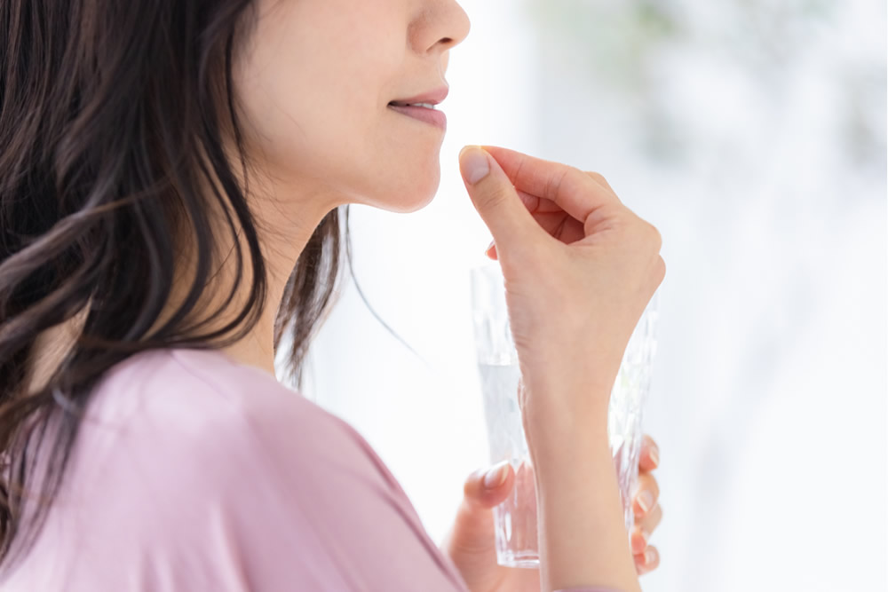 ピンクの服で薬を服用する女性