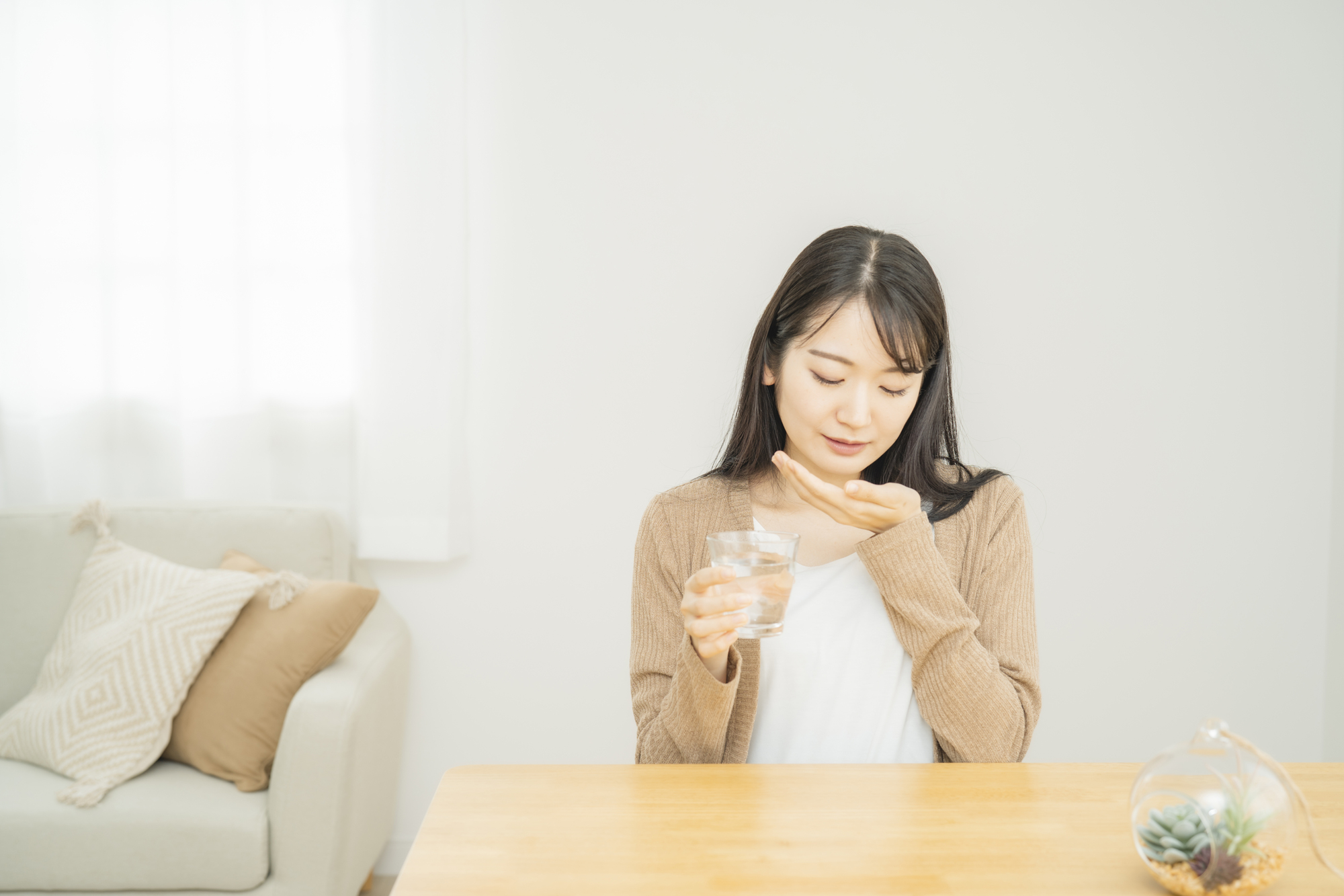 アフターピルとコップを手にしている女性