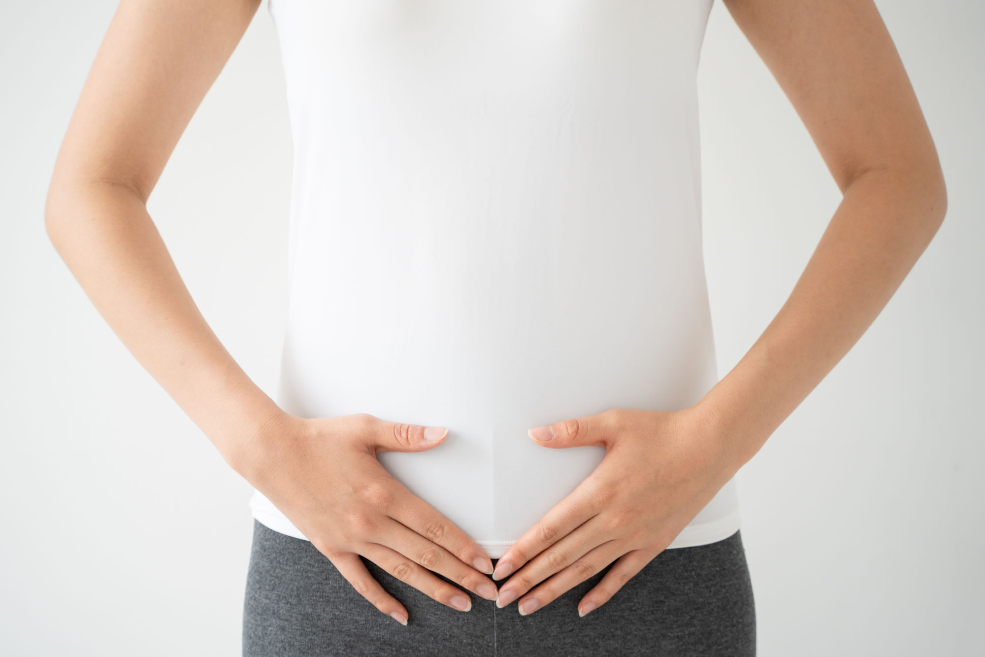 お腹に優しく手を当てている女性