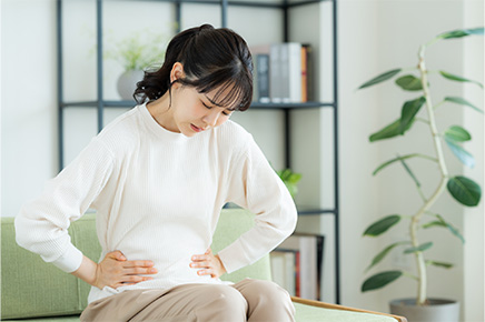 便秘で辛そうにする女性