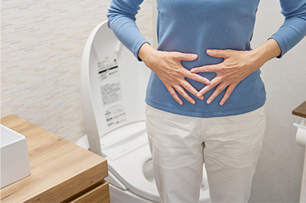 便秘になりトイレでお腹に手を当てる女性