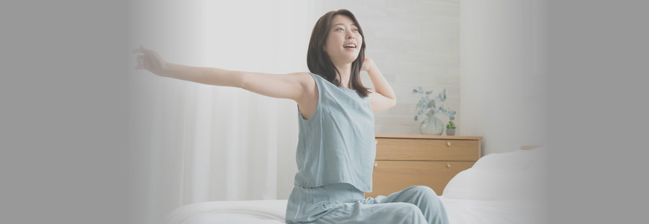 ベッドに座りお腹のストレッチをしている女性
