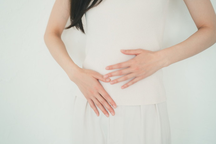 お腹を軽く抑えている女性