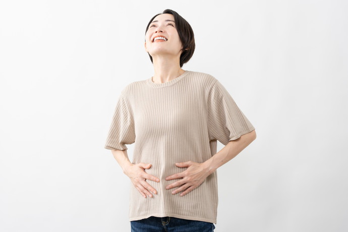 お腹をおさえて笑顔の女性