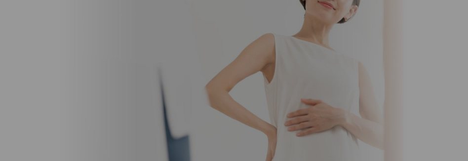 鏡を見てお腹を見ている女性