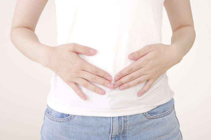 お腹を軽く抑えている女性