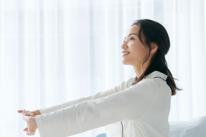 日光を浴びてストレッチをしている女性