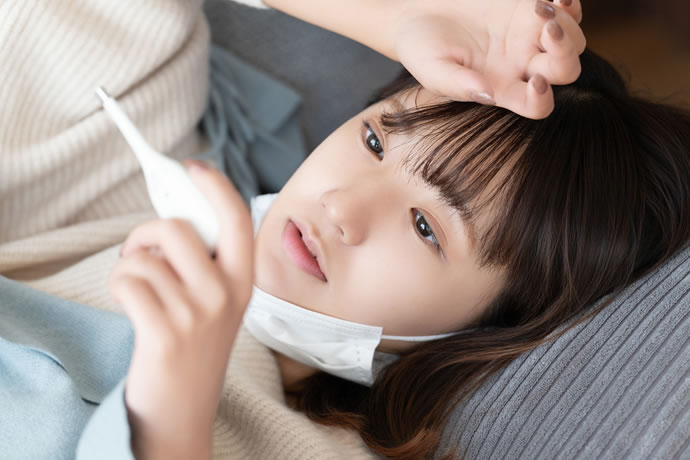 体温計を見て横になっている女性