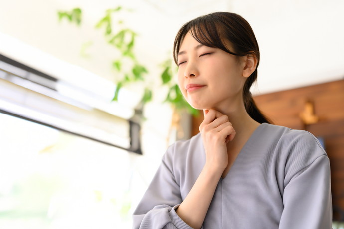 風邪で喉を抑えている女性