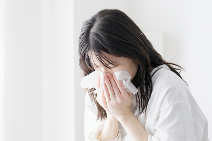 鼻を強くかんでいる女性