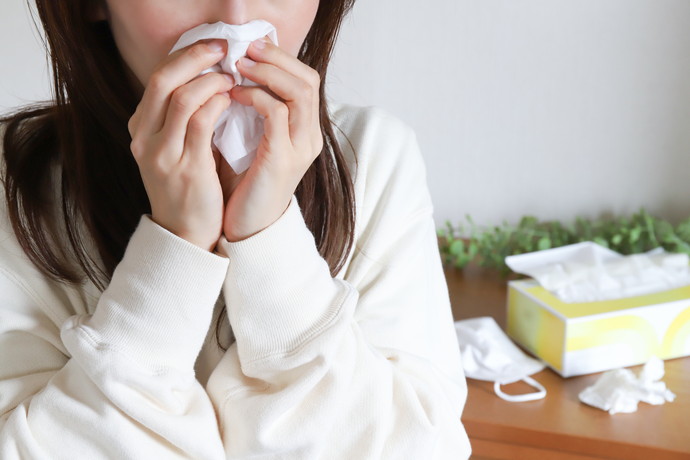 ティッシュで鼻をかんでいる女性