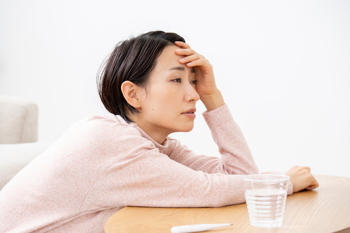 熱でテーブルで頭をかかえている女性