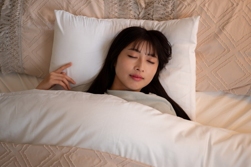 暗くしてベッドで寝ている女性