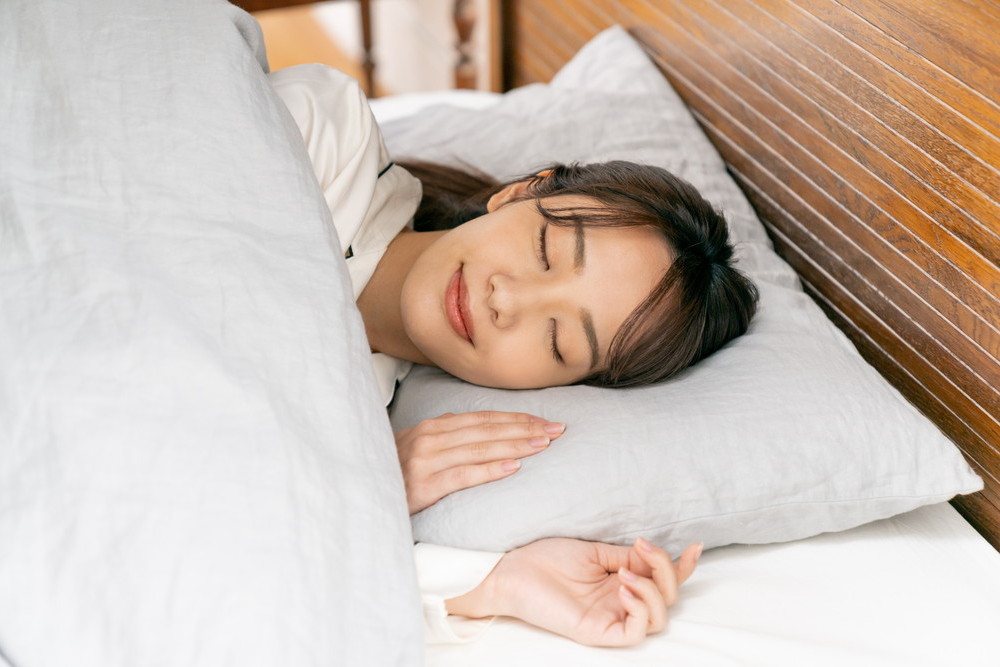横になってベッドで寝ている女性