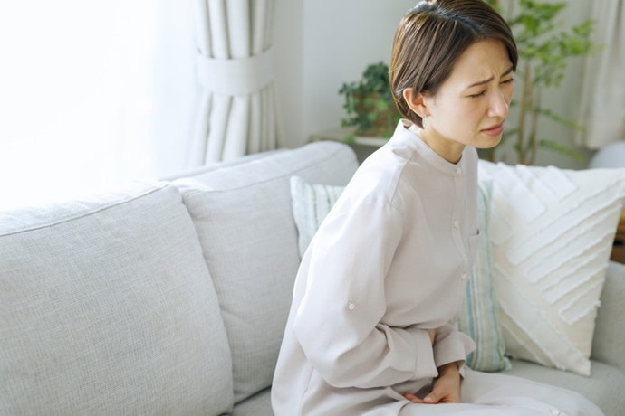 椅子に座ってお腹をおさえている女性