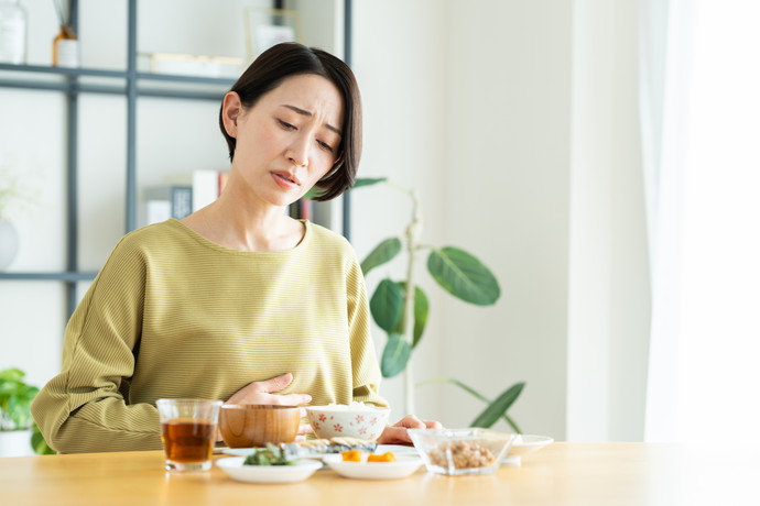 テーブルでお腹をおさえている女性