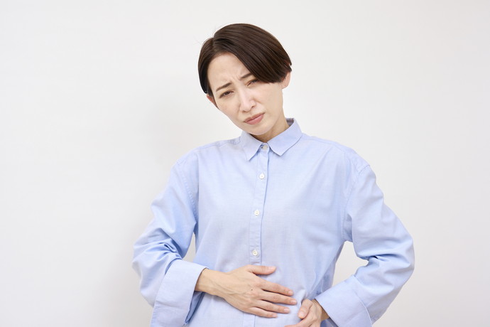 椅子に座ってお腹をおさえている女性