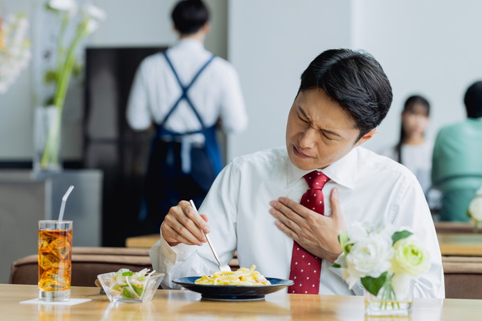 胸やけで胸をおさえている男性