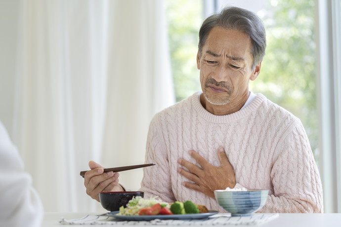 食事を食べづらそうにしている男性