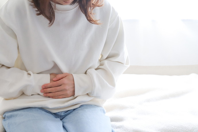 椅子に座って胃に不快感があって胃をおさえている女性