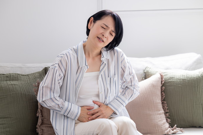胃に不快感があっておさえている女性
