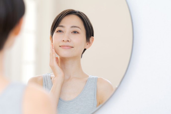 鏡で肌を見て笑顔の女性