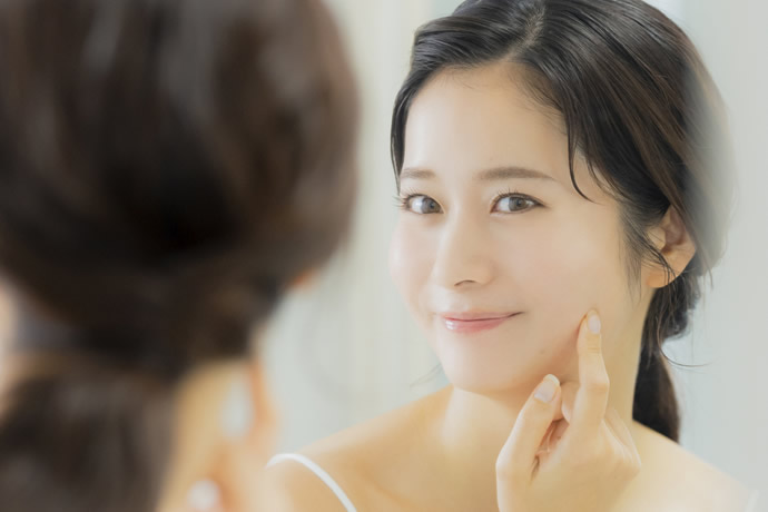 鏡を見て肌質をチェックしている女性